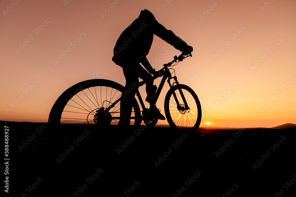 the fit cyclist successful ride and watch the sun from the summit mountains