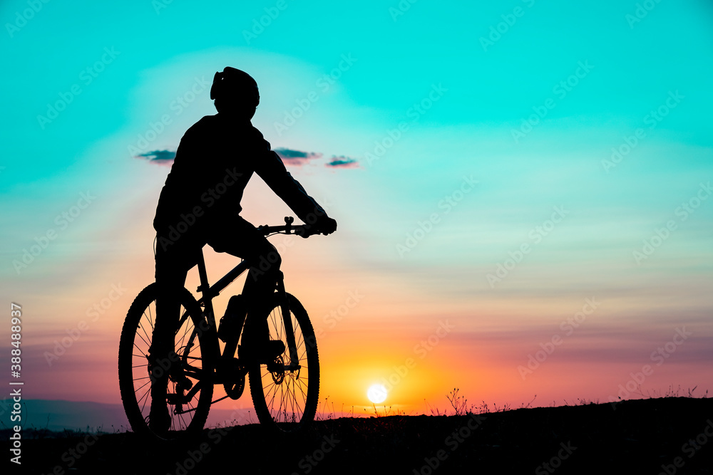 Obraz premium the fit cyclist successful ride and watch the sun from the summit mountains