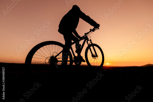 Fototapeta Naklejka Na Ścianę i Meble -  the fit cyclist successful ride and watch the sun from the summit mountains
