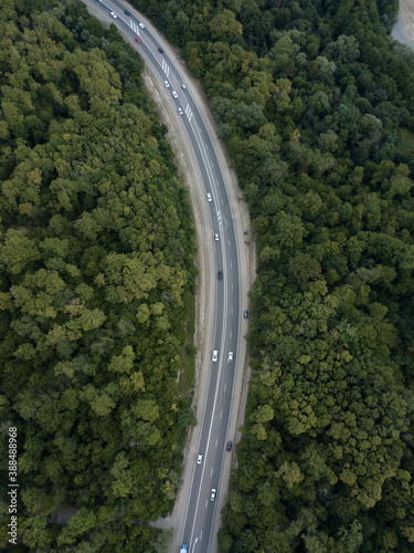 Aerial top down view of road in forest in mountains. Cars driving on highway in the woods. Summer landscape. Auto trip, Krasnodar krai Russia. © dimabucci