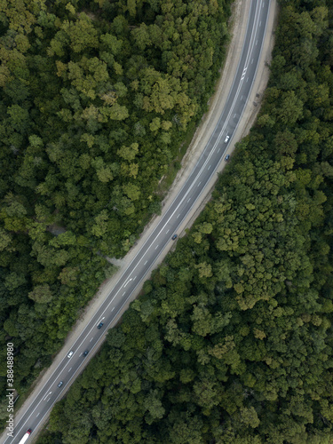 Aerial top down view of road in forest in mountains. Cars driving on highway in the woods. Summer landscape. Auto trip, Krasnodar krai Russia. © dimabucci
