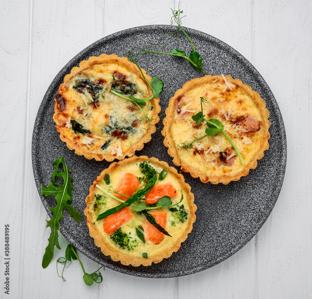 Tartlets with mushrooms, salmon and chicken on a wooden background.