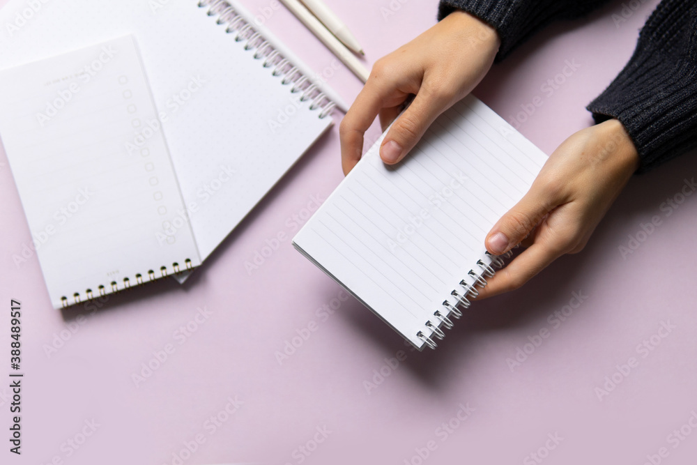 business composition with notebooks and pens on a pink background with a place to write. Business concept with hands holding notepad, writing text business composition with notebooks and pens on a pink background with a place to write. Business concept with hands holding notepad, writing text