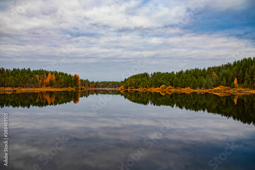 Autumn forest and sky reflected in water. Colorful autumn landscape.