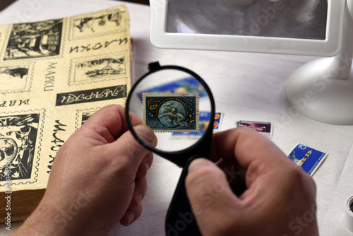 Moscow, October the year 2020. Through a magnifying glass in the hands of a philatelist examines the stamp. The stamp is dedicated to the 10th anniversary of the human spacewalk.