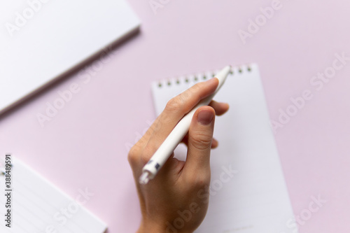 business composition with notebooks and pens on a pink background with a place to write. Business concept with hands holding a pen