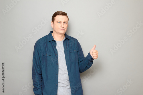 Portrait of disgruntled mature man showing thumb up gesture