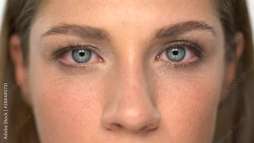 Close up of beautiful woman with blue eyes, looking at camera and blinking slowly