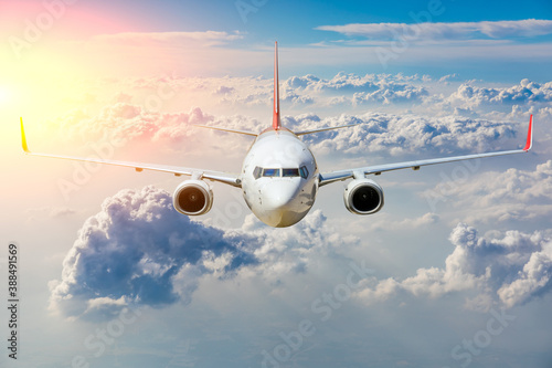 Commercial airplane flying above clouds in colorful sunset.Travel,holidays and business concept.