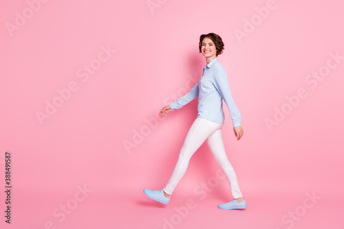 Full length body size profile side view of her she nice attractive lovely cheerful cheery skinny brown-haired girl walking copy space good mood isolated over pink pastel color background