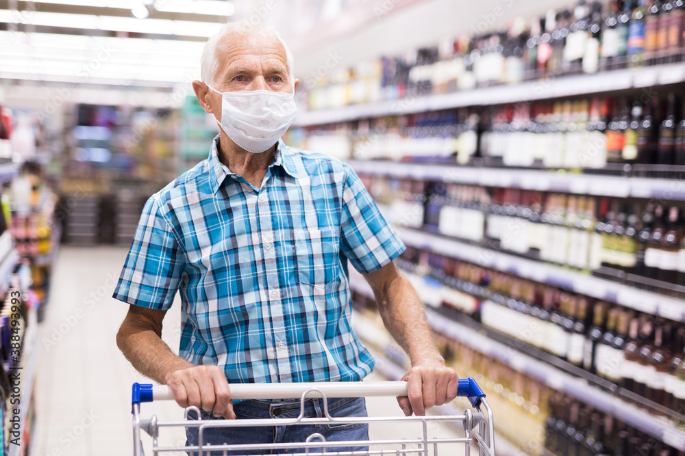 older european man wearing mask and gloves with covid protection shoping in supermarket