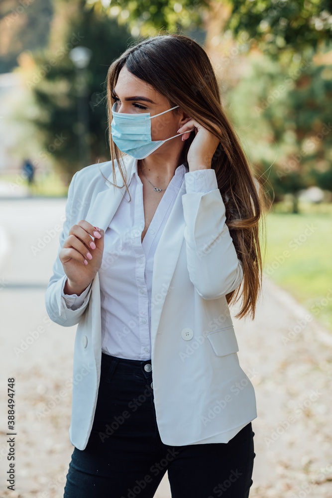 A beautiful businesswoman puts a surgical mask on her face. Prevention of coronavirus. 