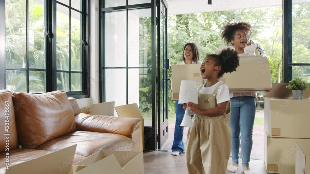 Happy African American young family bought new house. Mom, Dad, and child happy hold cardboard boxes for move object and having fun laugh into modern home. New real estate dwelling, loan and mortgage.