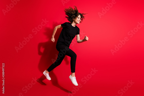 Photo portrait full body view of girl running jumping up isolated on vivid red colored background