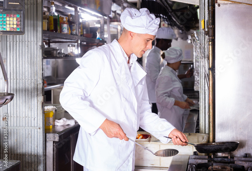 Portrait of professional responsible chef during carrying out daily duty in restaurant kitchen