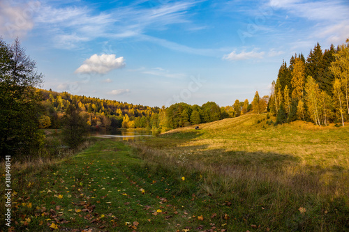 Green valley and blue sky on an autumn day. Colorful view of meadows and forest 