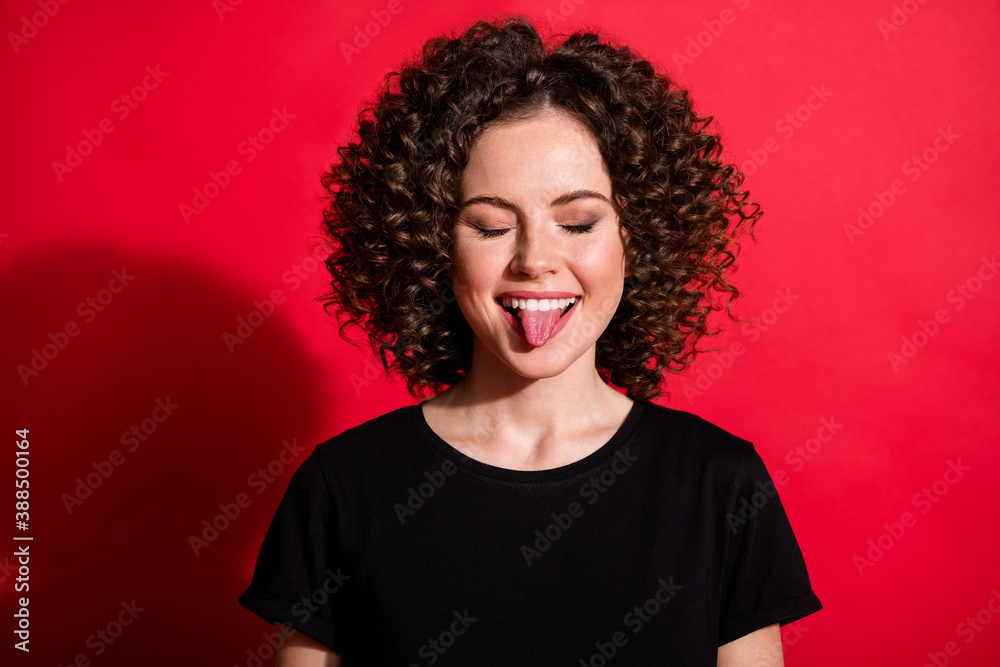 Close up portrait of cheerful person closed eyes bite tongue out nice outfit isolated on vivid red color background Close up portrait of cheerful person closed eyes bite tongue out nice outfit isolated on vivid red color background