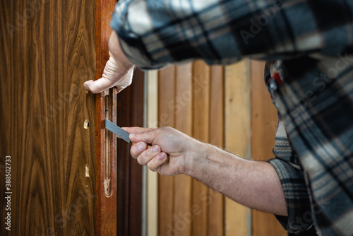 Close-up. Carpenter with the rasp prepares the hole for the lock of a wooden door. Construction industry. 