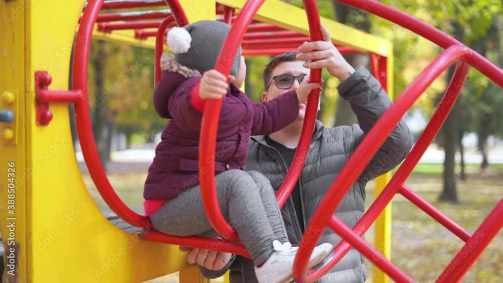 Father with child playing on playground, Autumn, yellow leaves. Outdoors kids activity