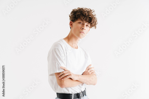 Young curly guy in t-shirt looking at camera with arms crossed
