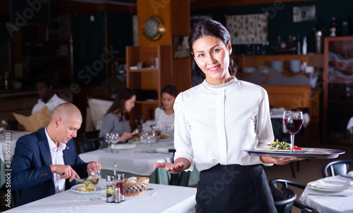 portrait of smiling female waiter standing in modern restaurante