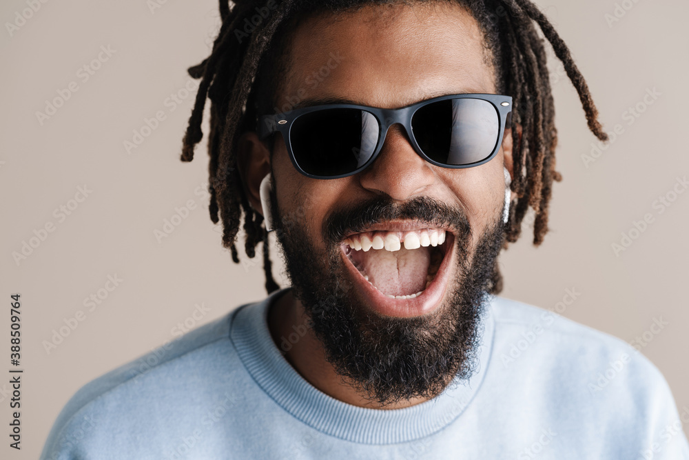 Cheerful african american guy in earphones laughing at camera Cheerful african american guy in earphones laughing at camera