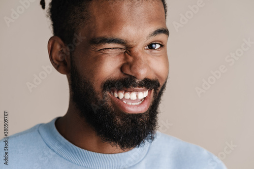 Joyful african american guy smiling and winking at camera