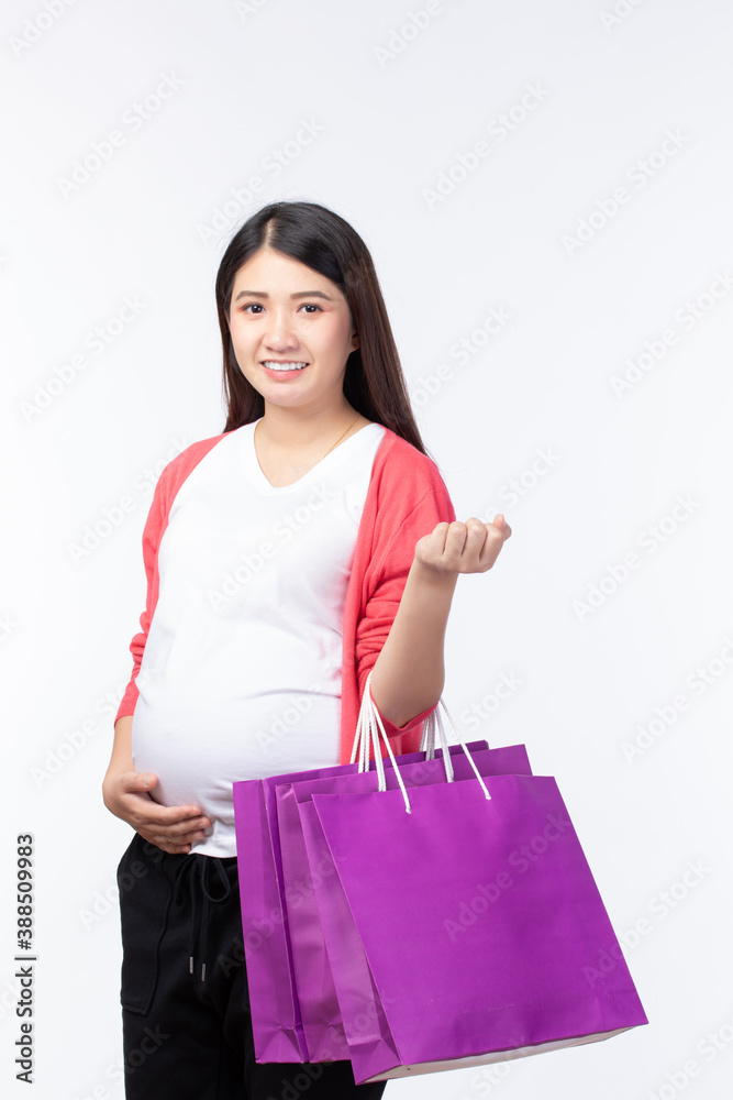 Portait happy young pregnant woman with shopping bags and touching her big belly on white background. Pregnancy shopping concept. Portait happy young pregnant woman with shopping bags and touching her big belly on white background. Pregnancy shopping concept.