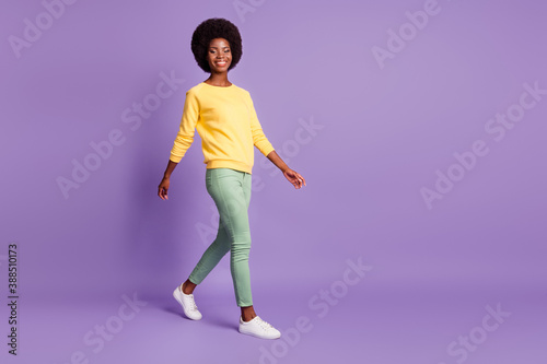 Full length profile side photo of positive afro ameriacn girl go empty space isolated over purple color background