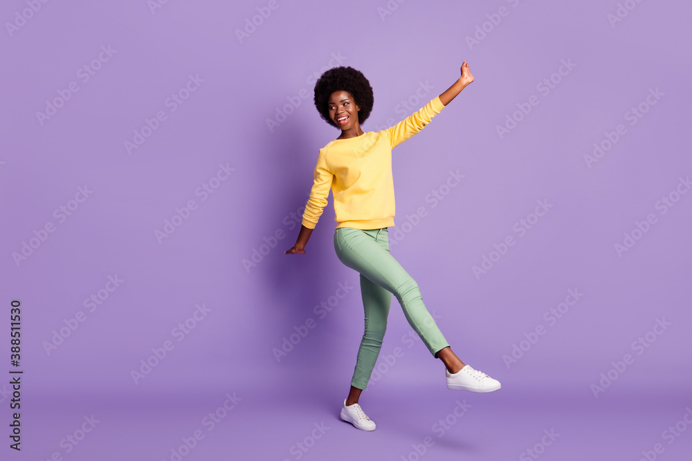 Full length photo of cute lady raise hands legs look empty space wear yellow pullover isolated purple color background