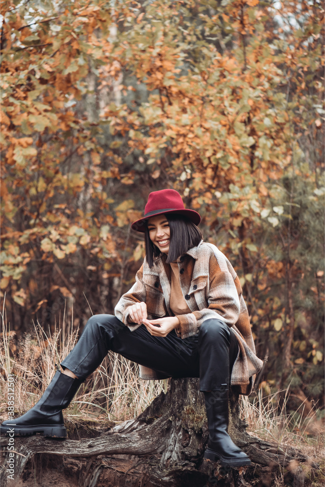 Young woman fashionably dressed in a dry autumn forest