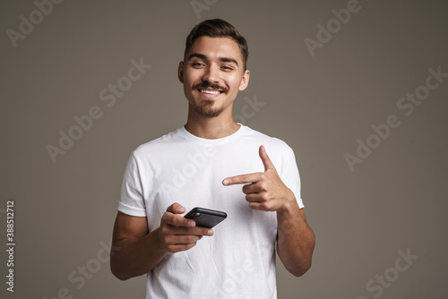 Image of joyful unshaven guy pointing finger at his cellphone © Drobot Dean