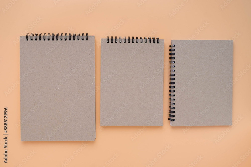 Top view above of Three school book brown closed spiral blank paper cover notebook isolated on brown background for design a mockup. Education and business concept. flat lay Top view above of Three school book brown closed spiral blank paper cover notebook isolated on brown background for design a mockup. Education and business concept. flat lay