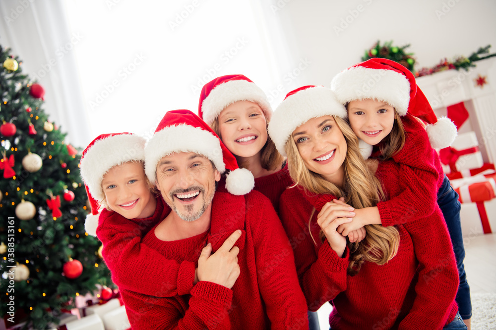 Full family tradition x-mas christmas tradition eve time. Small preteen kids hug embrace mommy mom daddy dad wear santa claus cap in house indoors with newyear garland tinsels Full family tradition x-mas christmas tradition eve time. Small preteen kids hug embrace mommy mom daddy dad wear santa claus cap in house indoors with newyear garland tinsels