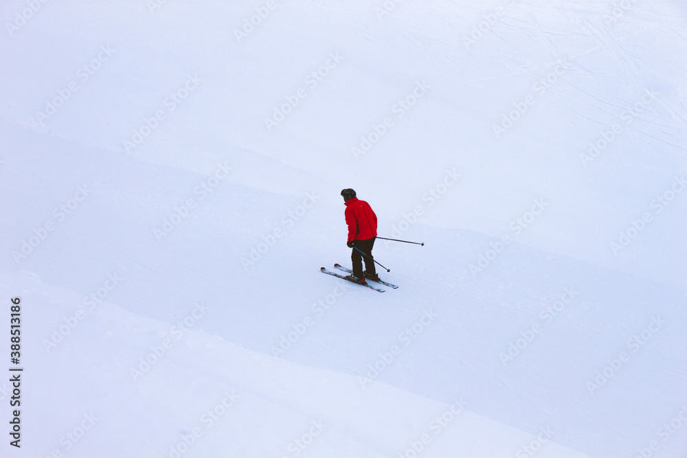 A man skier in a red jacket at snowy slope in mountains. Winter vacation. Grindelwald, Switzerland.
