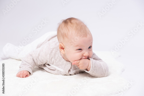 Charming baby is lying on the floor and sucking one’s small fingers