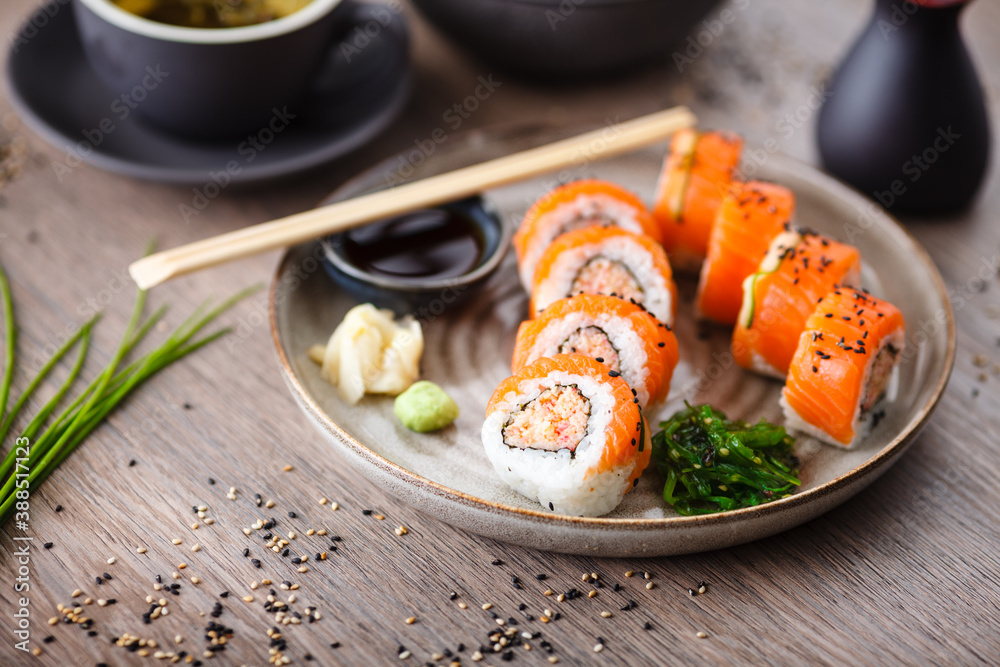 Sushi maki rolls with spicy crab, salmon, cucumber on a plate with chopsticks, soy sauce, wasabi and ginger. Japanese traditional seafood served for lunch in modern gourmet restaurant