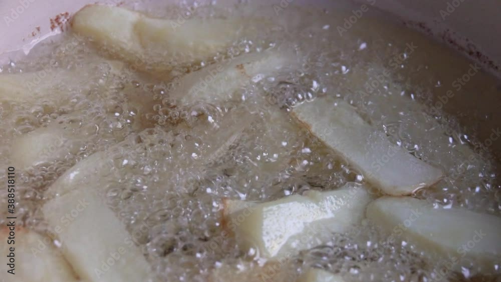 Close up of potatoes frying on hot boiling oil. Home made French fries fried in oil. Close up of potatoes frying on hot boiling oil. Home made French fries fried in oil.