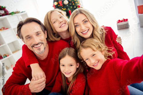 Closeup photo of full big family five people gathering three little kids embrace cuddle hold hands toothy smile wear red jumper in decorated living room x-mas tree garland indoors