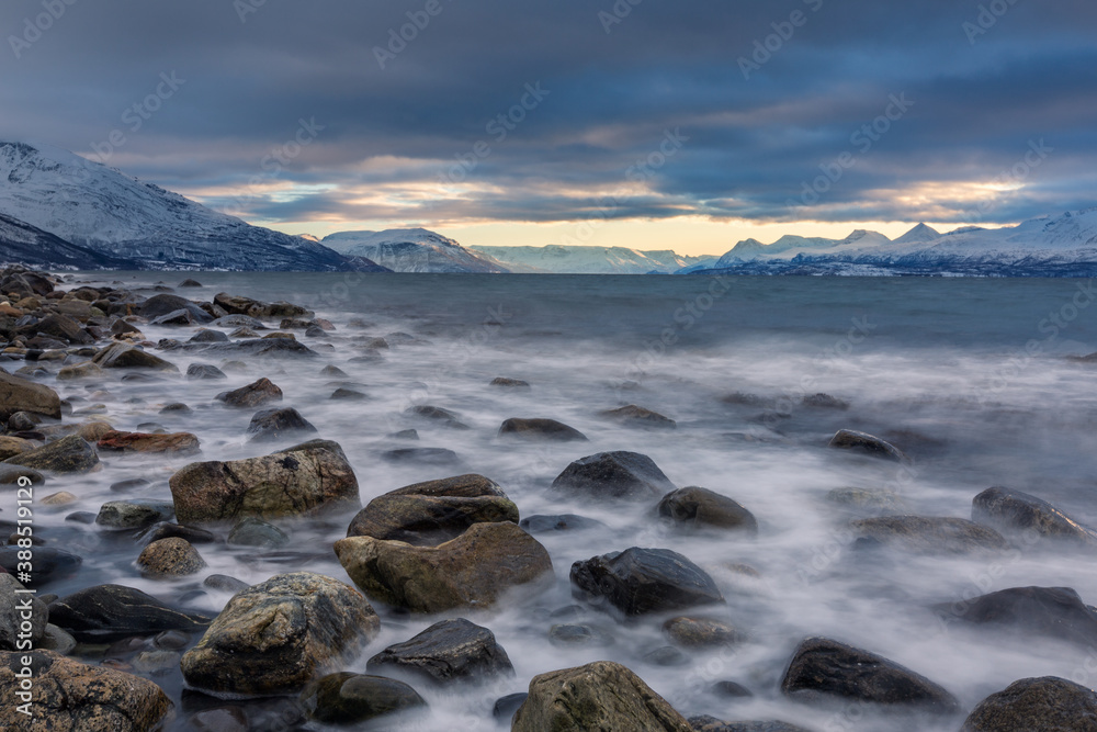 Beautiful stony seashore with blurred water and mountains on background