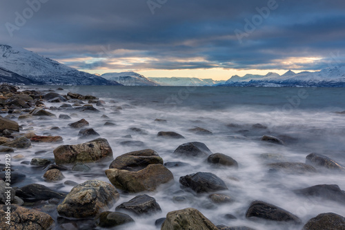 Beautiful stony seashore with blurred water and mountains on background