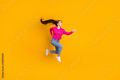 Full length profile photo of lovely lady jump air long hairstyle wear pink pullover jeans sneakers isolated yellow color background