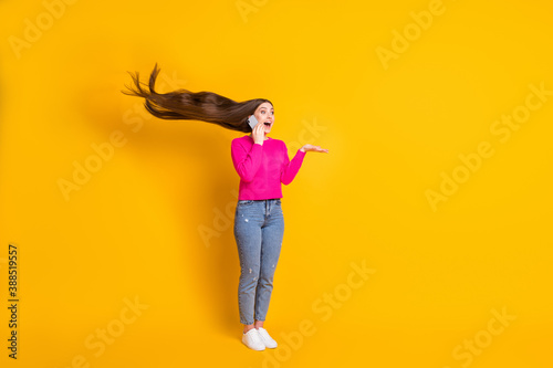 Full length photo of pretty lady talk telephone air blow long hairdo wear pink pullover jeans sneakers isolated yellow color background