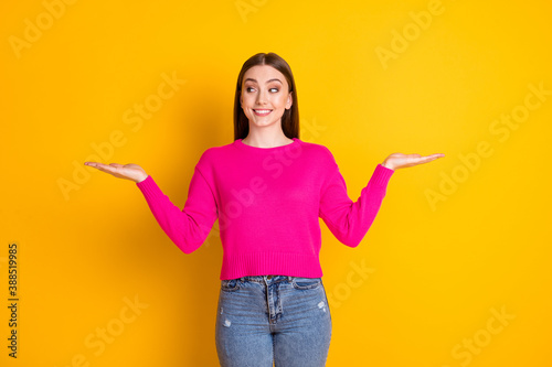 Photo of young lady raise two hands hold look empty space wear pink pullover jeans isolated yellow color background