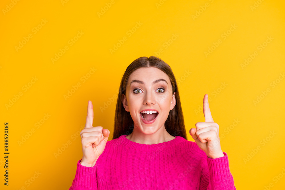 Photo of pretty girl direct fingers look up empty space amazed open mouth wear pink sweater isolated yellow color background Photo of pretty girl direct fingers look up empty space amazed open mouth wear pink sweater isolated yellow color background