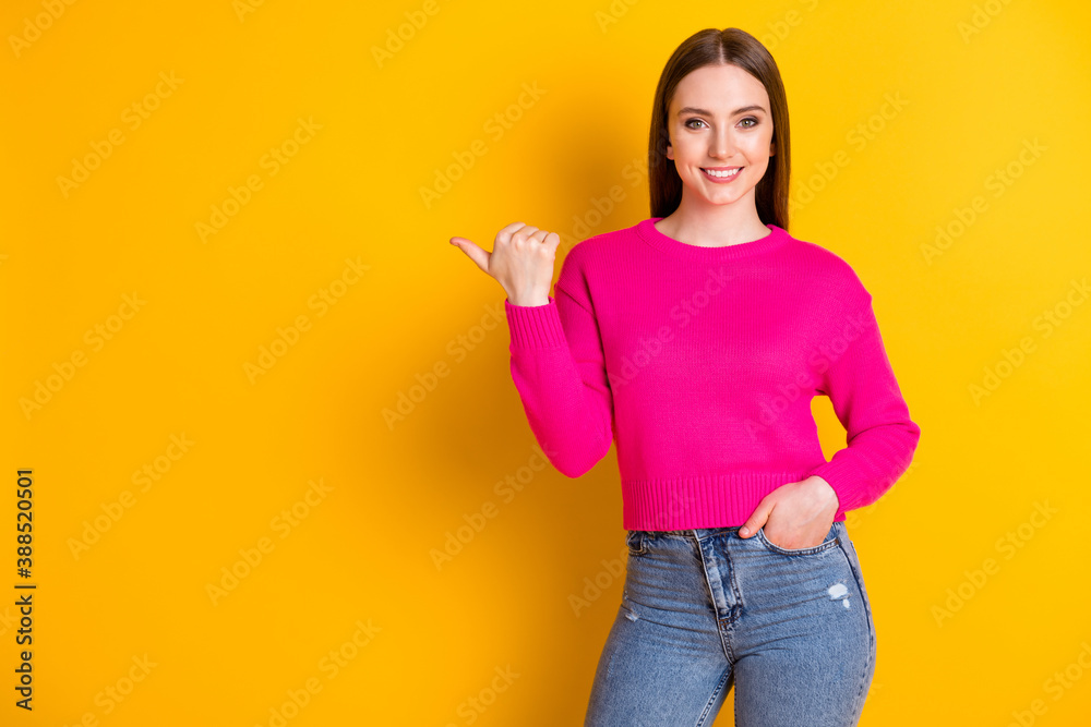 Photo of pretty young woman indicate finger empty space hand pocket wear pink sweater denim jeans isolated yellow color background Photo of pretty young woman indicate finger empty space hand pocket wear pink sweater denim jeans isolated yellow color background