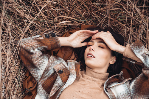 Beautiful woman lying on dry grass in autumn