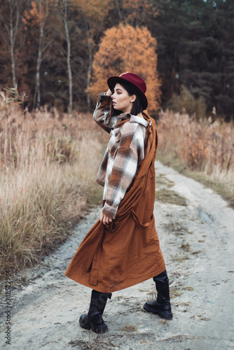 Fashionable woman in warm autumn clothes walks in the woods