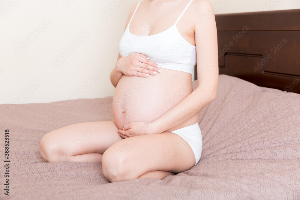 pregnant woman sitting in bed and touching her belly at home. pregnancy expectation concept pregnant woman sitting in bed and touching her belly at home. pregnancy expectation concept