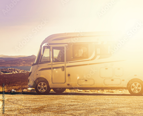 RV camper van parked in the mountains at sunset. Bright warm sunset blur. photo
